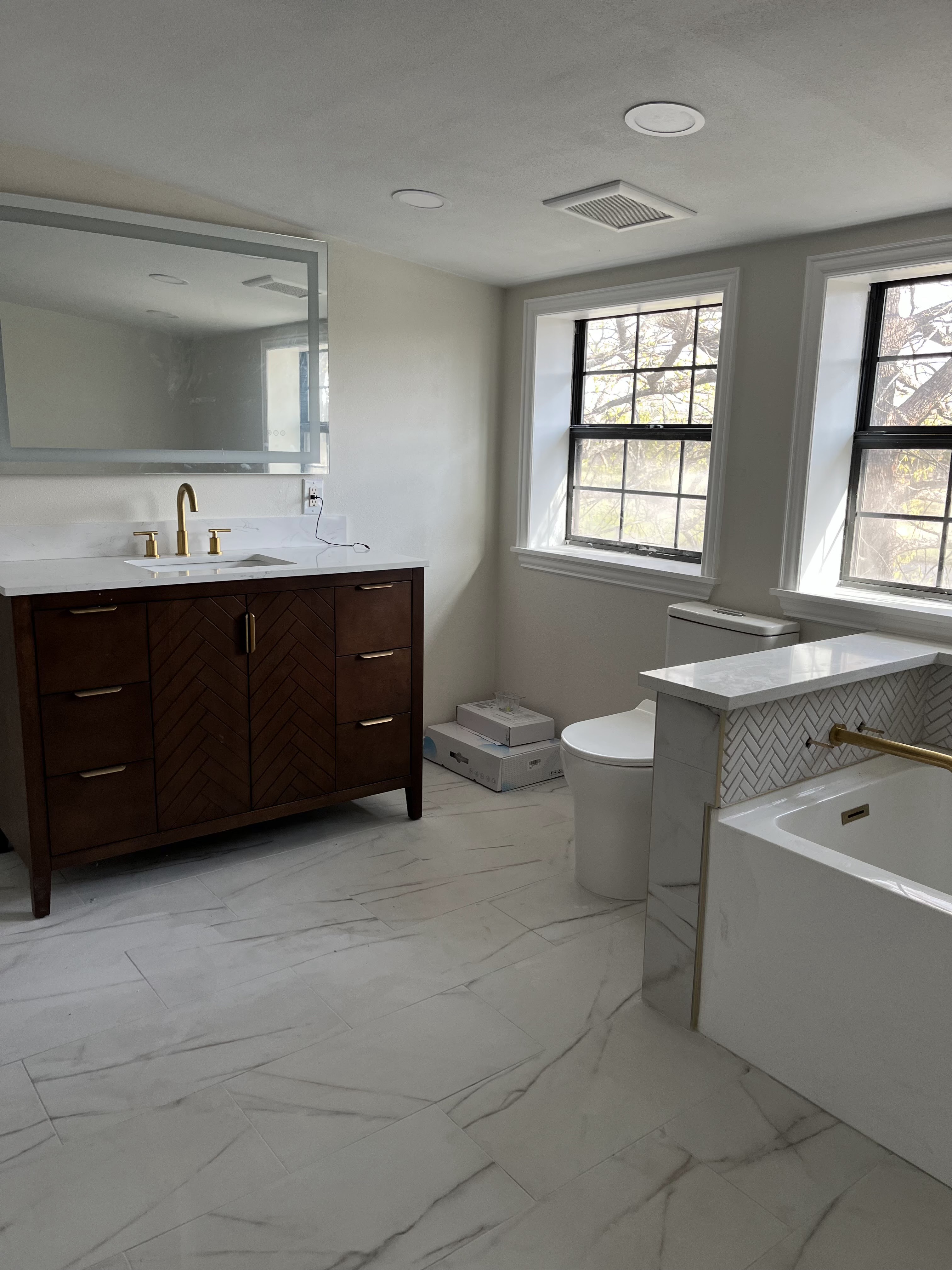Master bathroom remodel with dark herringbone vanity and freestanding tub