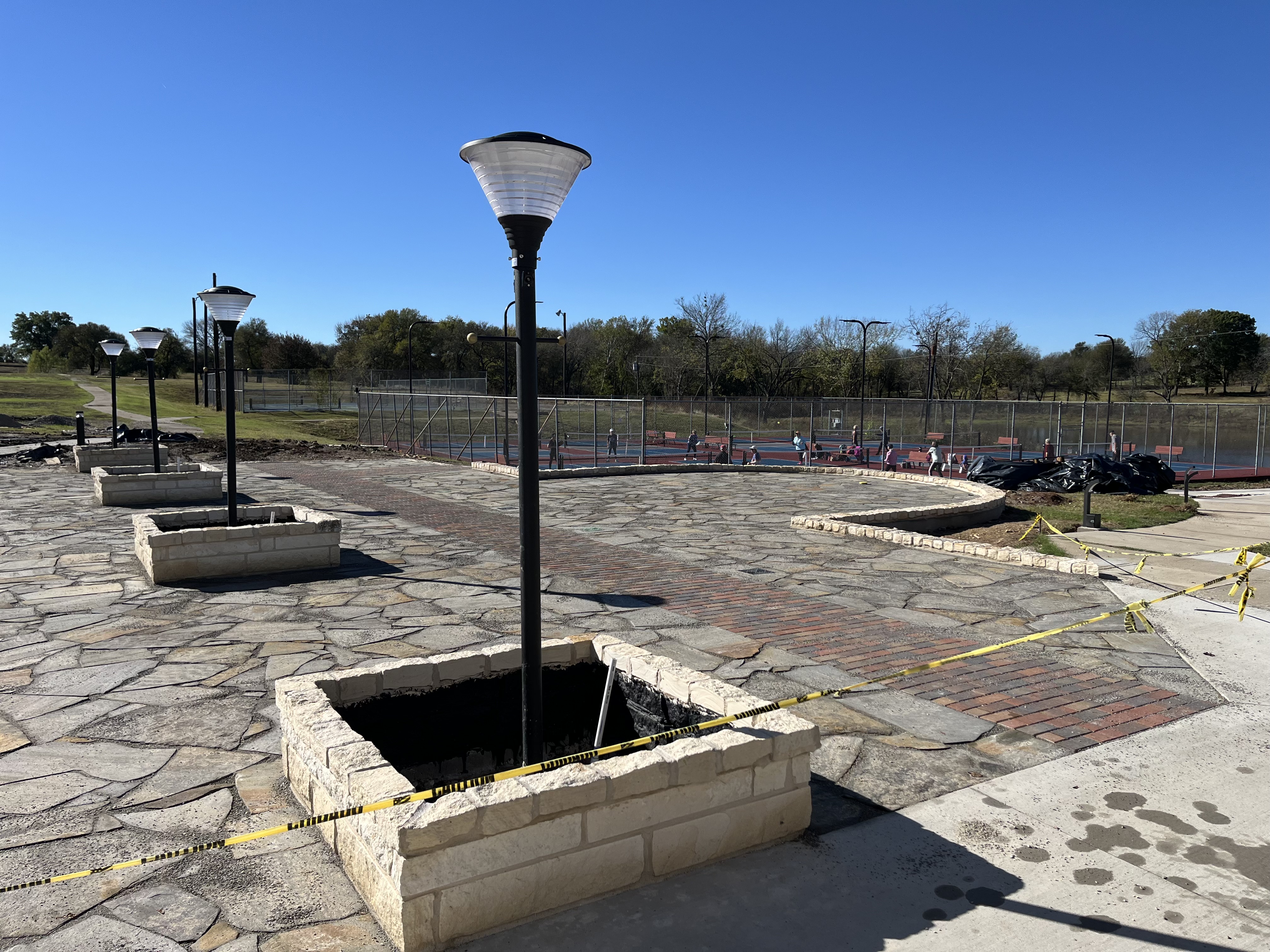 Stone patio plaza with lamp posts near tennis courts